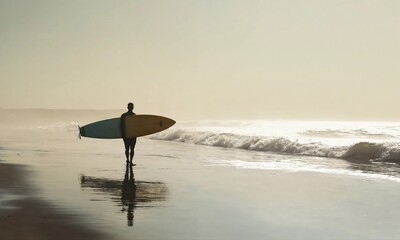 Surfers watch big breaking waves from beach after sunset surf session.