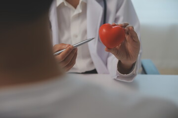 Hands of doctor woman holding red heart, showing symbol of love, human support to patient,...