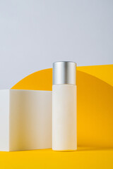 Plastic white tube for cream or lotion. Skin care or sunscreen cosmetic with stylish props on yellow background.