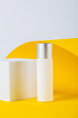 Plastic white tube for cream or lotion. Skin care or sunscreen cosmetic with stylish props on yellow background.