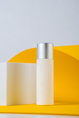 Plastic white tube for cream or lotion. Skin care or sunscreen cosmetic with stylish props on yellow background.