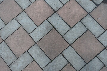 Dusty surface of geometric pavement made of grey and brown concrete tiles