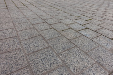 Close view of pavement made of gray unpolished granite stone blacks