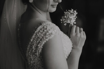 A woman is wearing a wedding dress and holding a flower. The image has a romantic and elegant mood