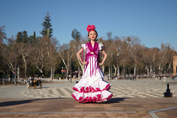 Girl dancing flamenco, posing looking at camera, in typical flamenco dress on a bridge in a nice square in Seville. Dance concept, flamenco, typical Spanish, Seville, Spain.