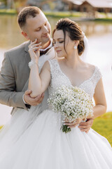 A bride and groom are posing for a picture. The bride is holding a bouquet of white flowers