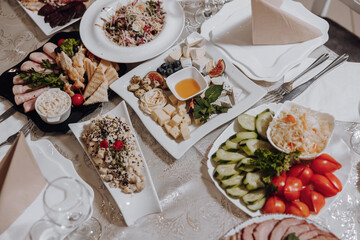 A table with a variety of food, including a salad, a plate of cucumbers, and a plate of tomatoes