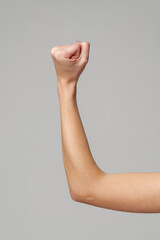 Female hand with clenched fist on gray background