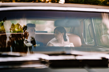 Valmiera, Latvia - August 19, 2023 - A bride and groom sit side by side in a classic car,...