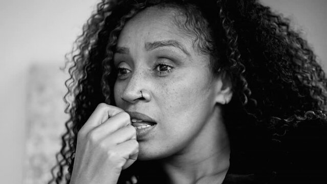 Nervous anxious African American middle-aged 50s woman struggles with angst in monochromatic, black and white close-up face