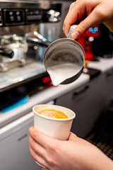 A skilled barista pours steamed milk into a cup of espresso, creating a delightful coffee in a modern cafe