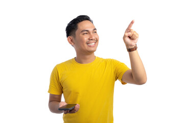 Happy young Asian man holding mobile phone and pointing finger in the air with big smile isolated on white background