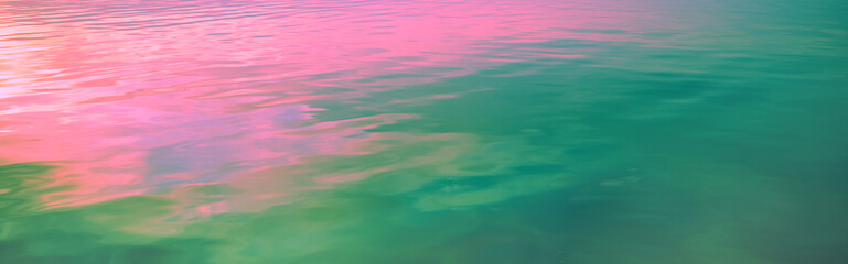 Sea water surface at sunset. View from above. Artistic pink blue gradient color. Horizontal banner