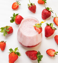 A strawberry milkshake or smoothie in a glass with strawberries on a white background