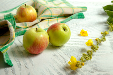 Three green apples on white wooden background..