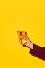 Male hand holding glass with lager beer against bright yellow background. Party time and refreshment. Concept of alcohol and non-alcohol drink, party, holidays, bar, mix. Poster. Copy space for ad - obrazy, fototapety, plakaty