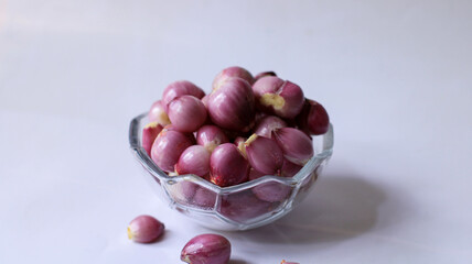 peeled red onion. complementary spices for cooking. peeled shallots in a glass bowl