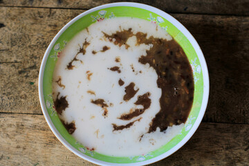 a bowl of green bean porridge with coconut milk sauce. bubur kacang ijo or mung beans porridge. The ingredients are mung beans