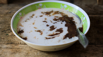 a bowl of green bean porridge with coconut milk sauce. bubur kacang ijo or mung beans porridge. The ingredients are mung beans