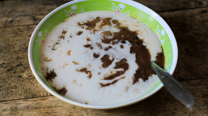 a bowl of green bean porridge with coconut milk sauce. bubur kacang ijo or mung beans porridge. The ingredients are mung beans