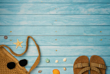 Flip flops, bag and sunglasses with shells on blue wooden background. Summer, vacations, beach...