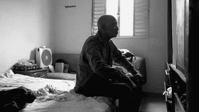 Serious Middle-Aged Man Reflecting on Life Struggles, Seated in Dimly Lit Room, Contemplating Poverty and Depression in black and white, monochrome