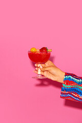 Human hand holding sweet and sour fruity cocktail with berries against pink background. Concept of alcohol and non-alcohol drink, party, holidays, bar, mix. Poster. Copy space for ad - obrazy, fototapety, plakaty