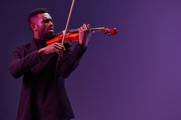 Soulful African American Man in Suit Playing Violin on Vibrant Purple Background in Studio Setting