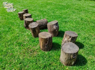 A route to be done barefoot: wooden logs on a lawn followed by one of rounded stones. Beautiful sunny day.