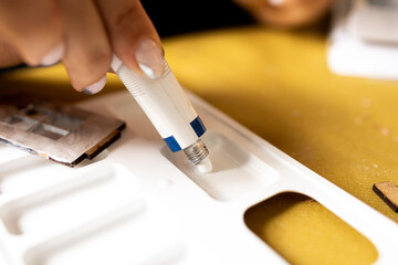 A girl squeezes acrylic paint from a tube onto an art palette. A woman is preparing to paint with...