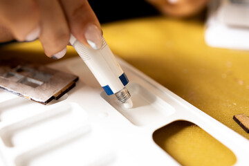 A girl squeezes acrylic paint from a tube onto an art palette. A woman is preparing to paint with white paint.