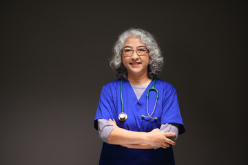 Portrait of friendly mature female doctor with stethoscope around her neck standing on black...