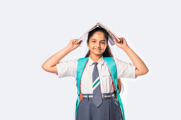 Indian asian pretty schoolgirl in school uniform holding books, standing against white background
