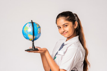 Asian Indian schoolgirl wears school uniform standing against white background holding globe