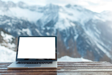Blank screen view of laptop on wooden table with ice mountains background. Mockup
