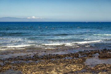 Beach on the island of Tenerife formed with volcanic rocks with the Atlantic Ocean and some surfers...