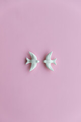 Two white swallows on pink background