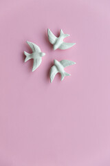 Three white swallows on pink background