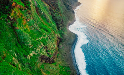 Aerial view of rough blue ocean with waves, volcanic beach in Teleférico das Achadas da Cruz, Madeira, Portugal