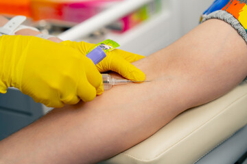 close-up in the clinic doctor in yellow gloves takes blood for tests from a patient