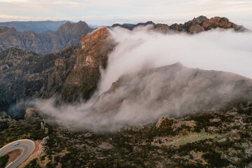 Aerial view of majestic mountain ridges at sunrise with falling fog from top of Pico do Areeiro, Madeira island, Portugal