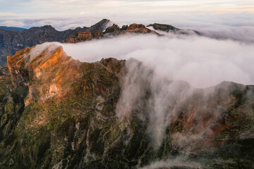 Aerial view of majestic mountain ridges at sunrise with falling fog from top of Pico do Areeiro, Madeira island, Portugal