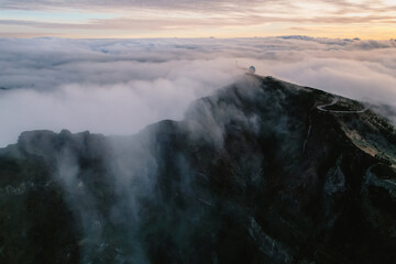 Aerial view of majestic mountain ridges at sunrise with falling fog from top of Pico do Areeiro, Madeira island, Portugal