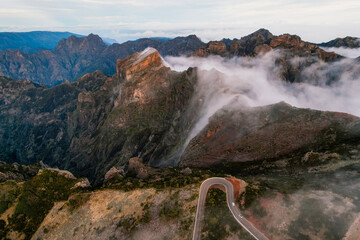 Aerial view of majestic mountain ridges at sunrise with falling fog from top of Pico do Areeiro, Madeira island, Portugal