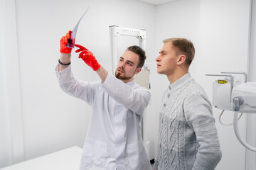 in a private clinic in white x-ray room the doctor shows the patient a picture of the back