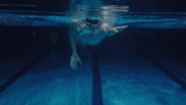 Man swimming front crawl style in a pool POV underwater