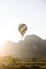 colorful hot air balloon rising over mountain range at sunset in Vang Vieng, the adventure capital of Laos
