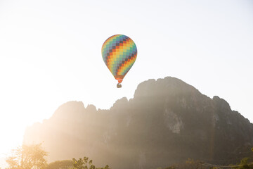 colorful hot air balloon rising over mountain range at sunset in Vang Vieng, the adventure capital of Laos