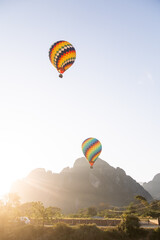 colorful hot air balloons floating over a mountain range in Vang Vieng, the adventure capital of Laos