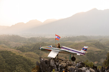 Fototapeta na wymiar tourists waving a flag in abandoned airplane on top of a mountain viewpoint in Vang Vieng, the adventure capital of Laos